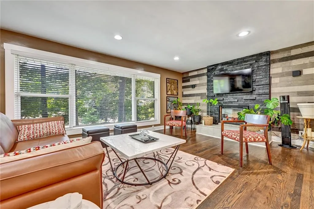Living room featuring wooden walls, recessed lighting, a stone fireplace, and wood finished floors