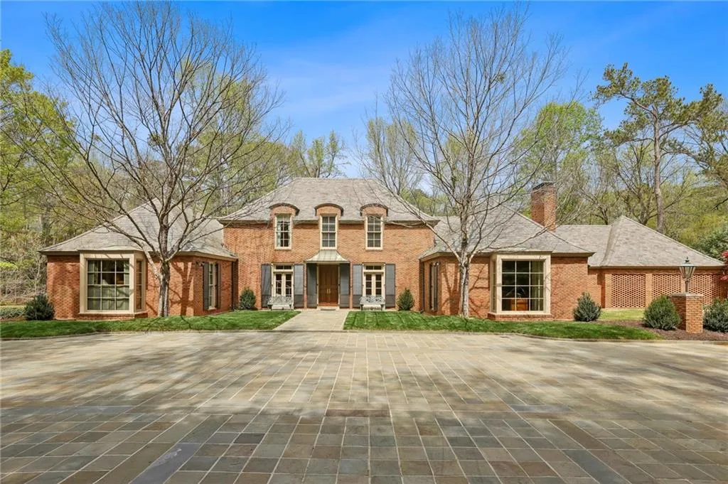 French country inspired facade with brick siding and a chimney