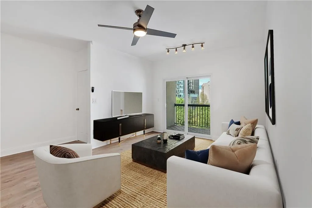 Living area featuring light wood-type flooring, a ceiling fan, track lighting, and baseboards