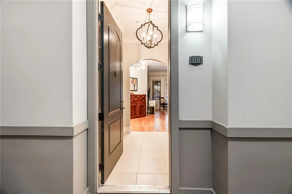 Hall featuring arched walkways, a chandelier, and light tile patterned flooring