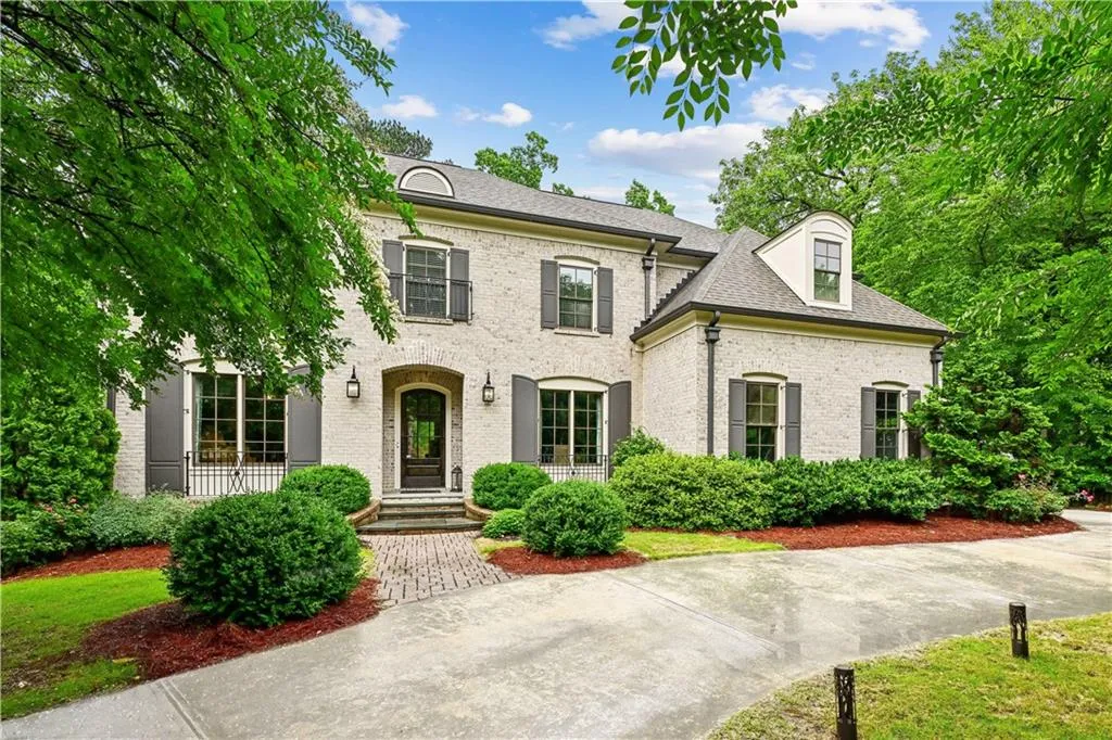 French country style house with brick siding and a shingled roof