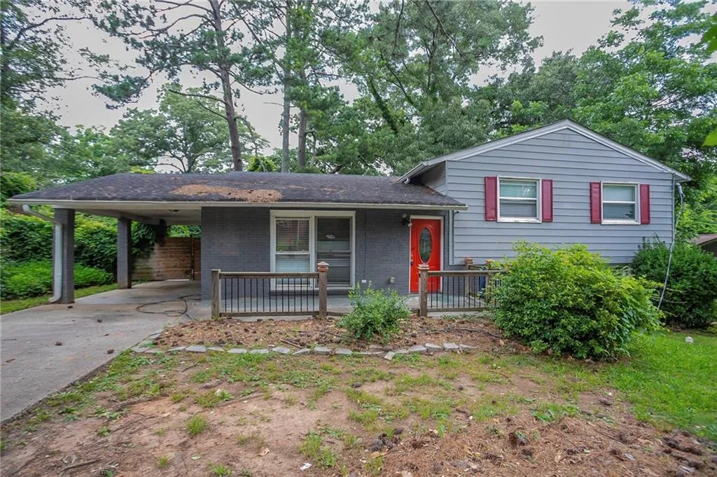 Tri-level home featuring covered porch, an attached carport, driveway, and brick siding
