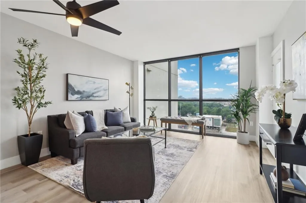 Living room featuring light wood-style floors, ceiling fan, floor to ceiling windows, and baseboards