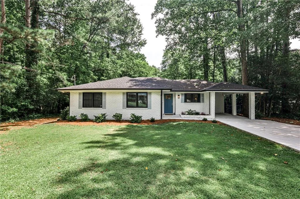Ranch-style home with driveway, a carport, a front yard, brick siding, and a shingled roof