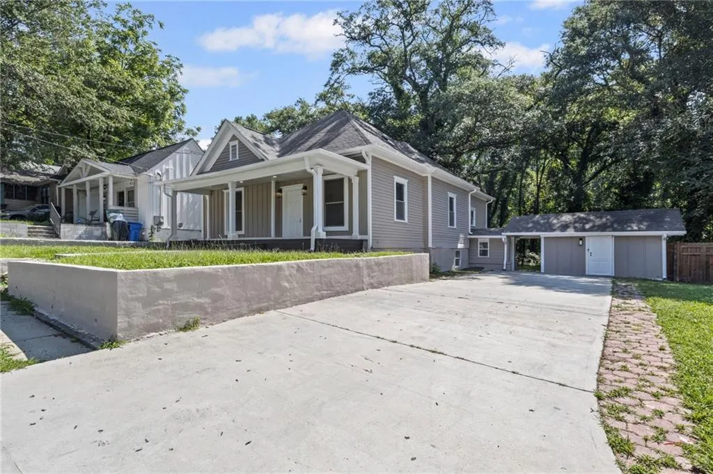 View of front facade with a porch, driveway, and an outdoor structure