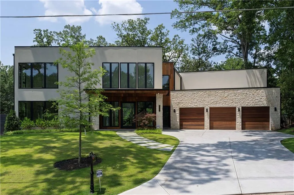 Contemporary home with stone siding, concrete driveway, an attached garage, a front lawn, and stucco siding