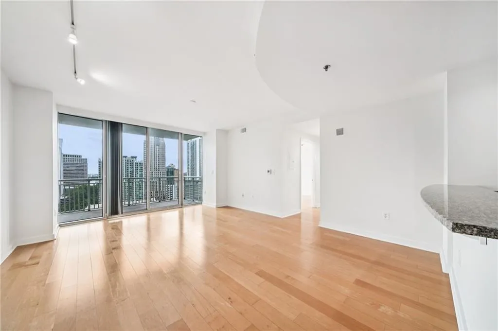 Unfurnished living room with a wall of windows, light wood finished floors, a city view, and rail lighting