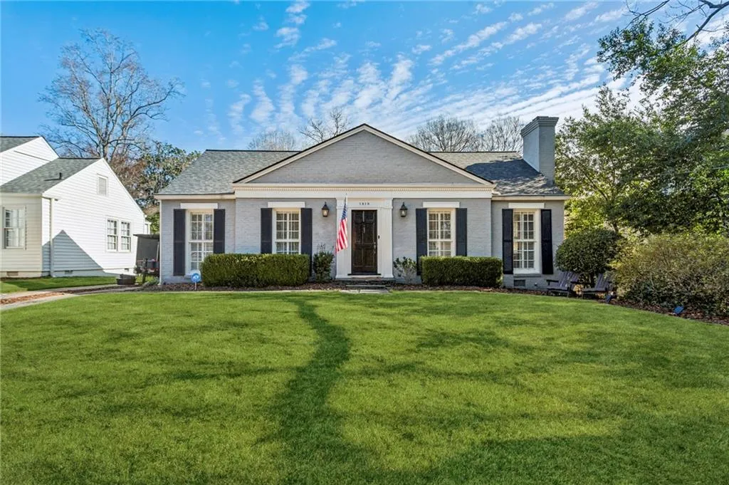 View of front of house with a chimney, a front lawn, and brick siding