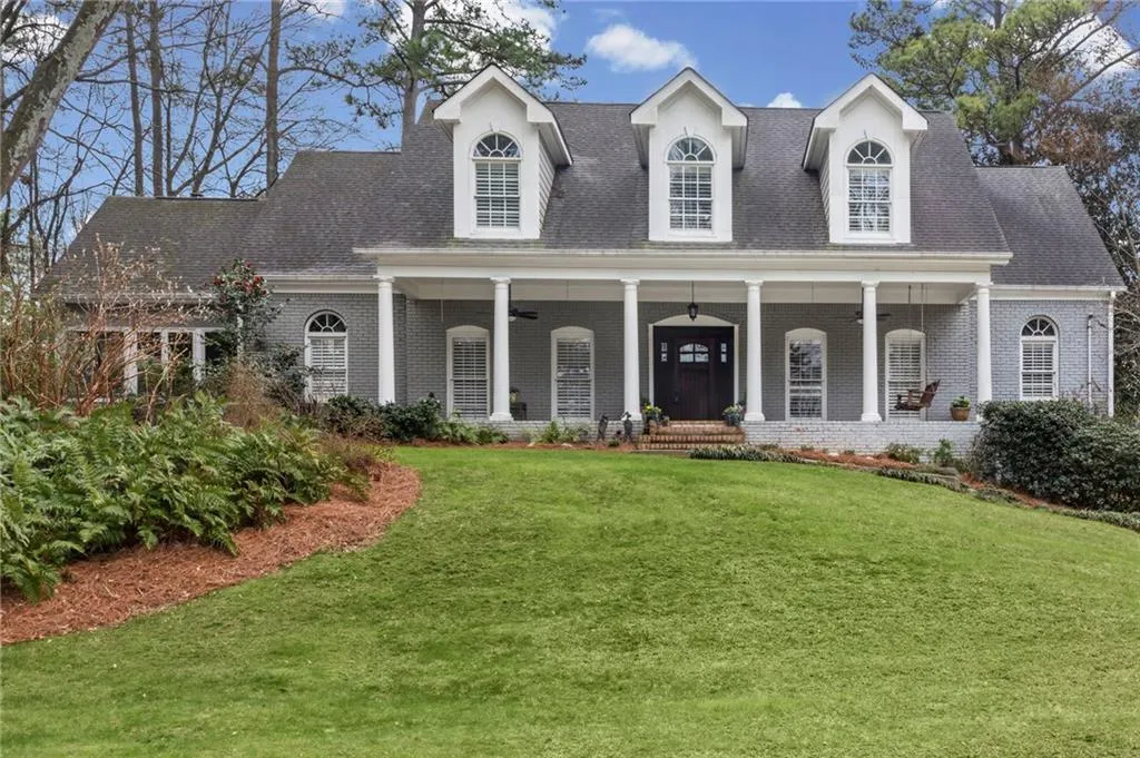 Cape cod-style house featuring a porch, a front yard, brick siding, and roof with shingles