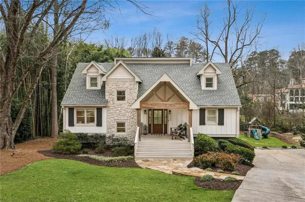 View of front of property featuring a shingled roof, board and batten siding, a front yard, covered porch, and stone siding